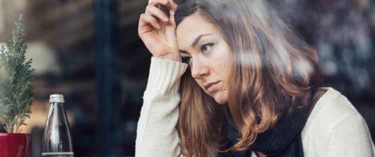 Photo of a woman looking stressed, resting her head in her hand