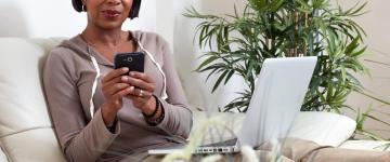 African American woman looking at phone at home